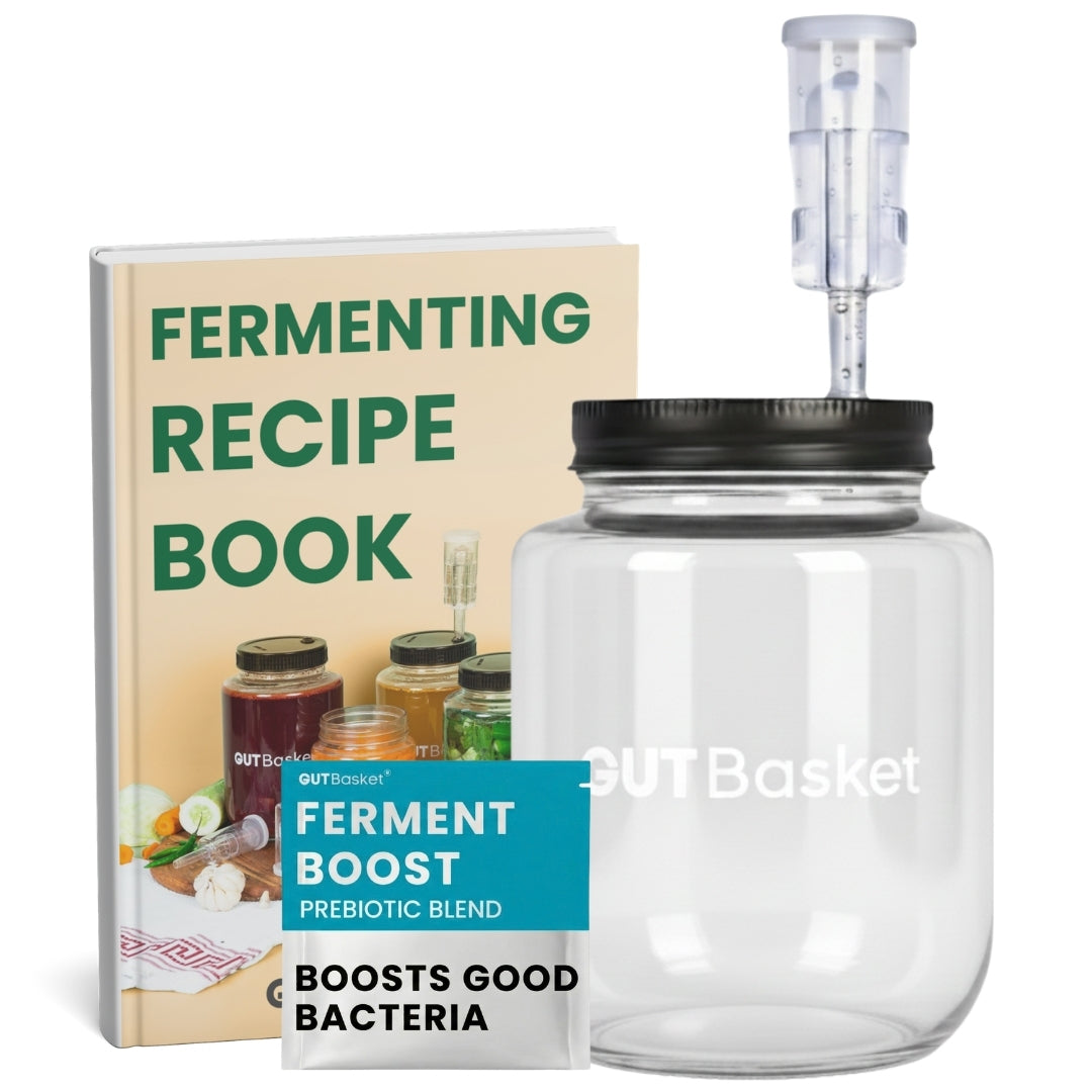 Clear glass jar with black lid and GUTBasket ferment boost blend next to a 'Fermenting Recipe Book'.